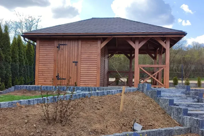 a18-1-stylowa-drewniana-altana-ogrodowa Altana A18 to wyjątkowe połączenie funkcjonalności i estetyki, idealnie wpisujące się w każdą przestrzeń ogrodową. Dzięki przestronnej konstrukcji, która łączy altanę o wymiarach 3,00m x 3,50m z domkiem o wymiarach 1,80m x 3,50m, stanowi idealne miejsce do relaksu, przechowywania i spotkań na świeżym powietrzu.