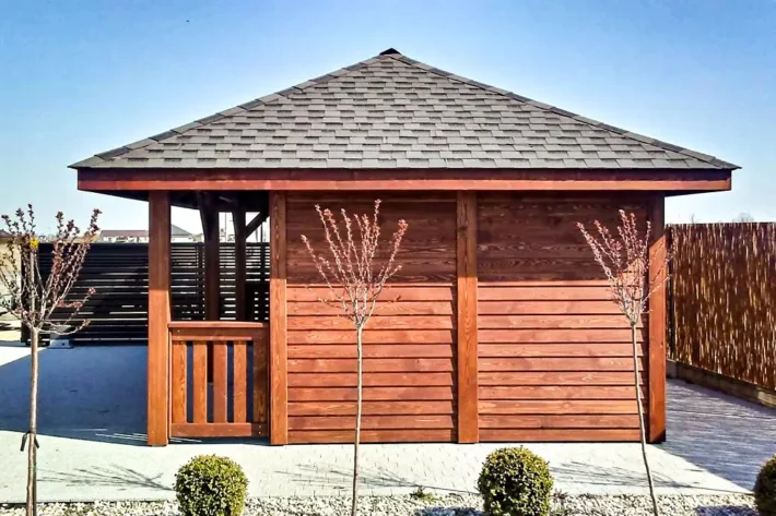 a19-5-stylowa-drewniana-altana-ogrodowa Altana A19 to elegancka i funkcjonalna konstrukcja, która doskonale łączy przestrzeń wypoczynkową z praktycznym domkiem, idealnym do przechowywania lub dodatkowego użytku. Całkowity wymiar altany wynosi 6,00m x 4,00m, z czego altana zajmuje 4,40m x 4,00m, a domek 1,60m x 3,00m. Przed domkiem znajduje się uroczy tarasik o wymiarach 1,60m x 1,00m, który stanowi doskonałe miejsce na relaks.