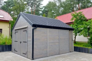 Garaż typu STODOŁA G1 to stylowa i funkcjonalna konstrukcja, która doskonale sprawdzi się na każdej posesji. Dzięki nowoczesnej formie i solidnym materiałom, garaż zapewnia nie tylko praktyczne miejsce do przechowywania pojazdu, ale także estetyczny element architektury ogrodowej. Wymiary garażu wynoszą 4,10m x 6,10m, z przestrzenią garażową o powierzchni 5,50m x 4,10m oraz dodatkowym zadaszeniem o wymiarach 0,60m x 4,10m.